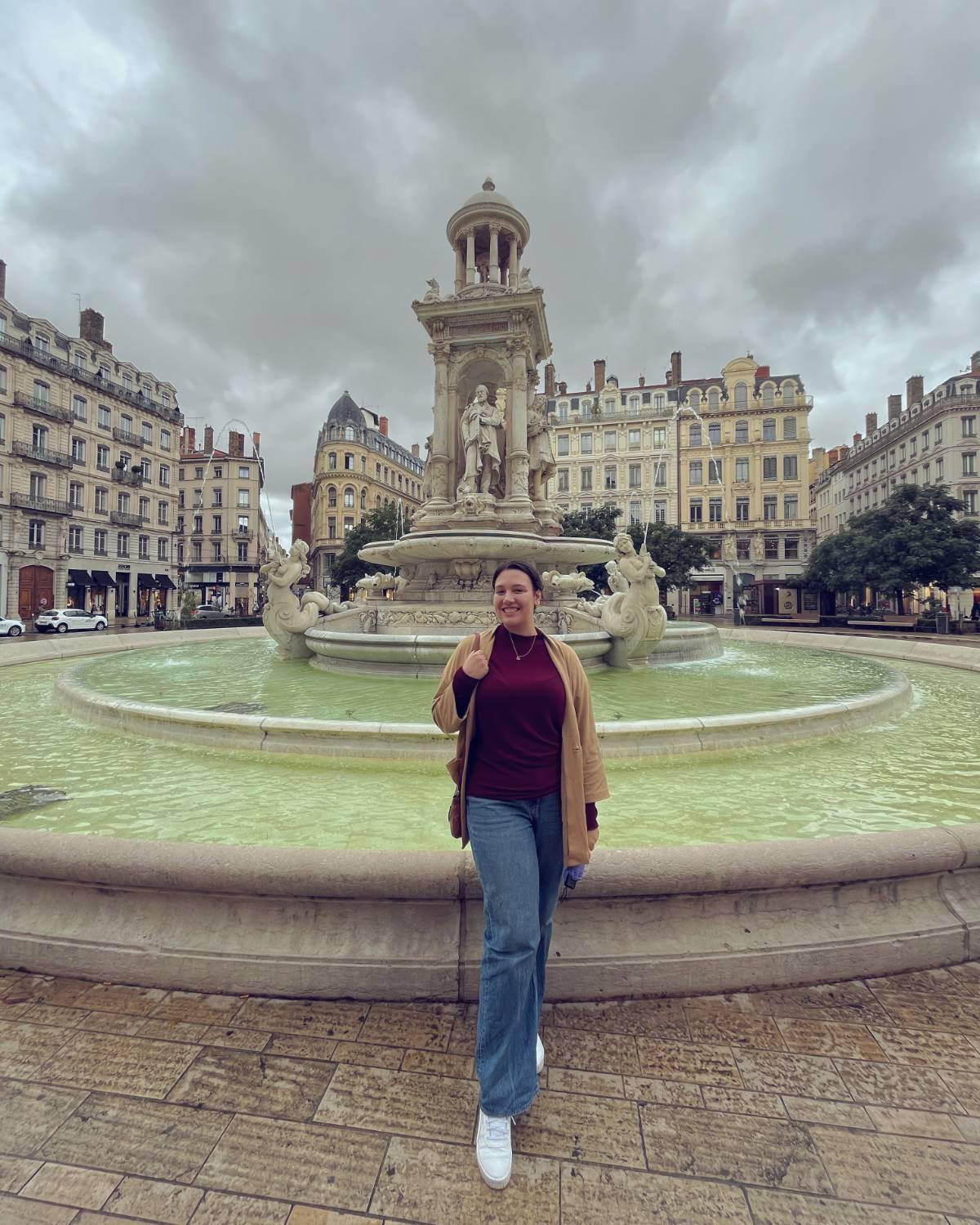 Madison Creech in front of an intricate fountain with old buildings behind it